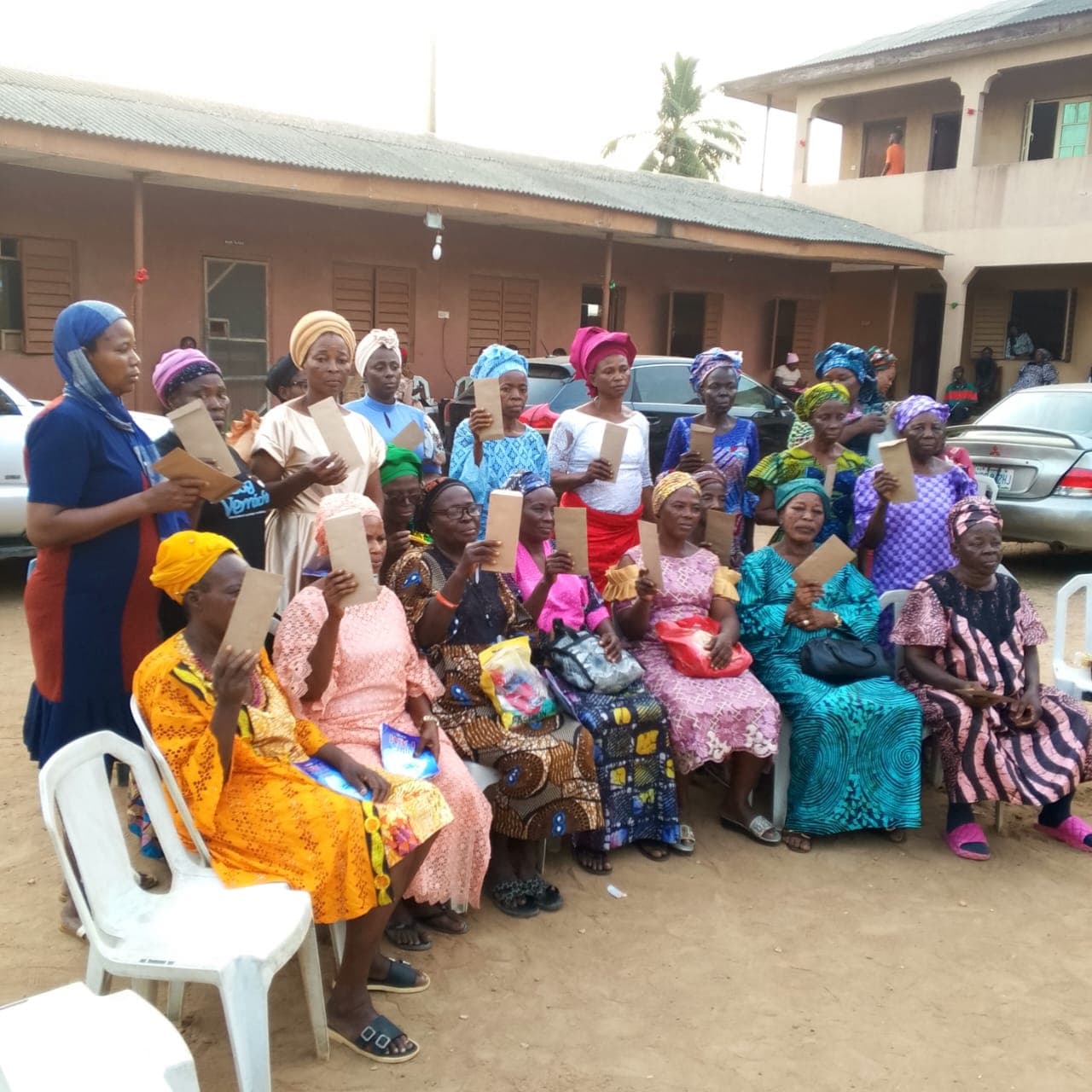 Group portrait of widows holding tokens of encouragement in the courtyard